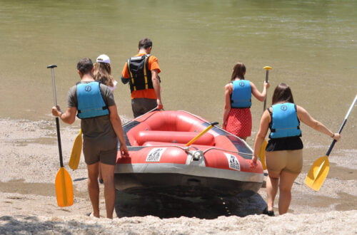 Five people getting ready to enter the river with a rafting boat