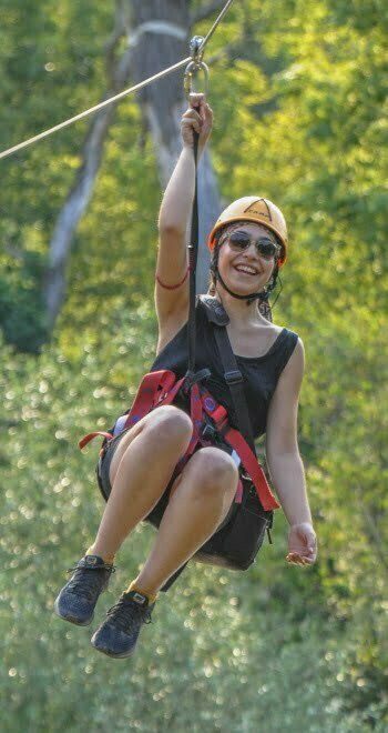 A young woman doing zip-line smiling